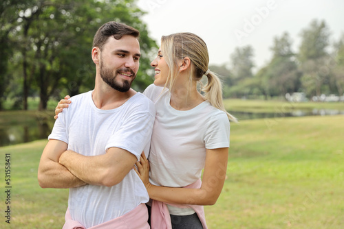 young couple caucasian people are in love. man and girl wearing white shirt hugging in the park during summer season with smiling and happy face