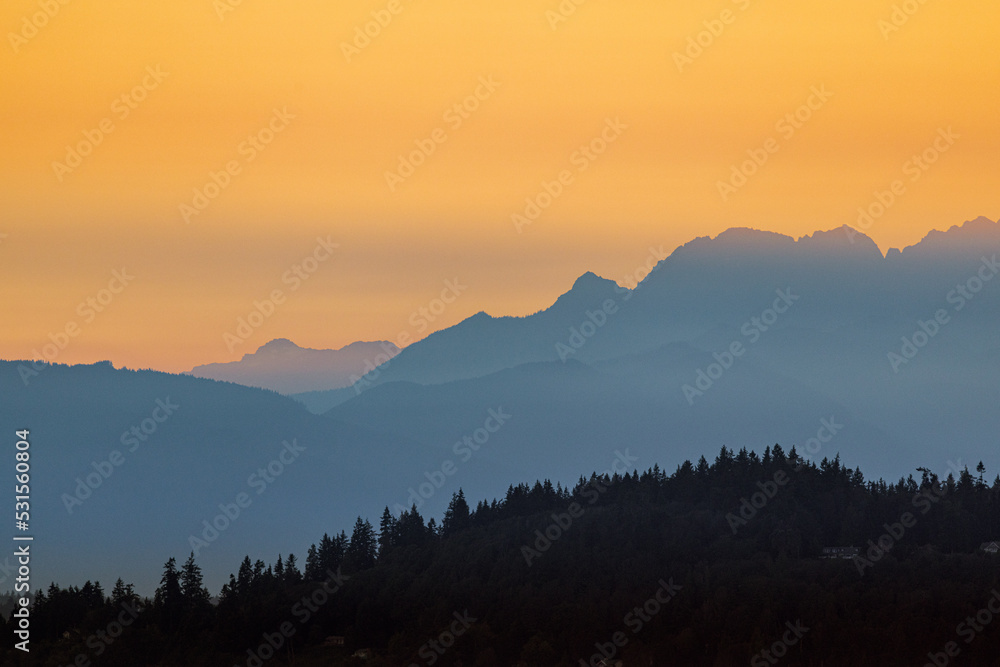 Sunset falls over Puget Sound casting a golden hue over the hills and Olympic Mountains