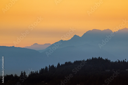 Sunset falls over Puget Sound casting a golden hue over the hills and Olympic Mountains