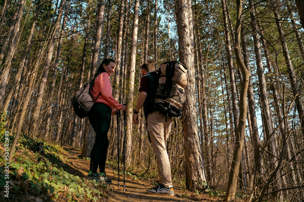 Young couple hiking together through the forest  