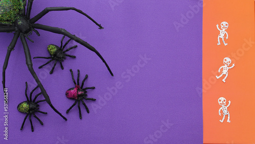 Arañas caminando y esqueletos bailando sobre fondo morado con franja anaranjada.  photo