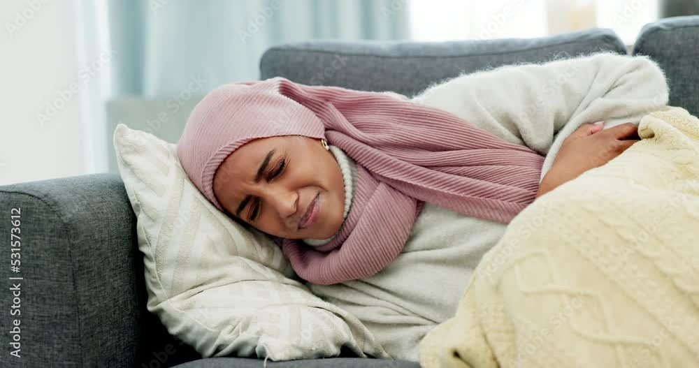 Muslim, period cramps and woman with stomach ache pain lying on sofa feeling sick due to endometriosis at home. Unhappy Islamic person with abdomen, belly and digestive problems due to menstruation Muslim, period cramps and woman with stomach ache pain lying on sofa feeling sick due to endometriosis at home. Unhappy Islamic person with abdomen, belly and digestive problems due to menstruation