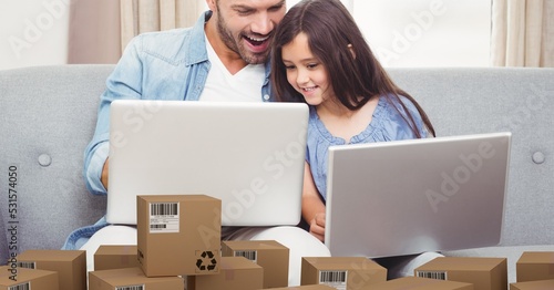 Caucasian dad and his daughter using laptop shopping online with a pile of boxes
