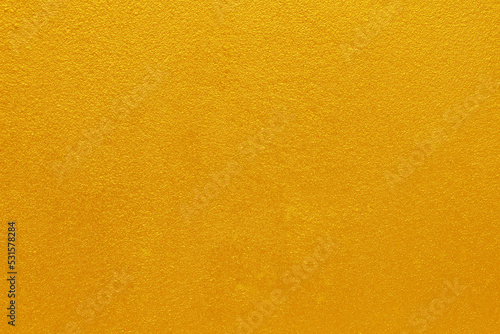 Gold or yellow paint on cement wall texture background.