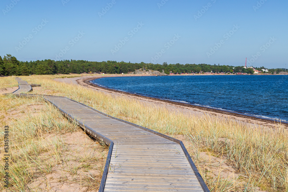 Wooden boardwalk at the Tulliniemi beach in Hanko, Finland, on a sunny day in the summer.