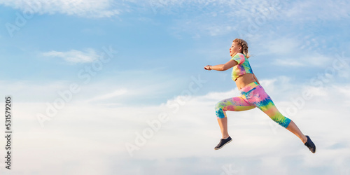 Young girl gymnast flies in long jump against background of blue summer evening sky. There is no ground under your feet.
