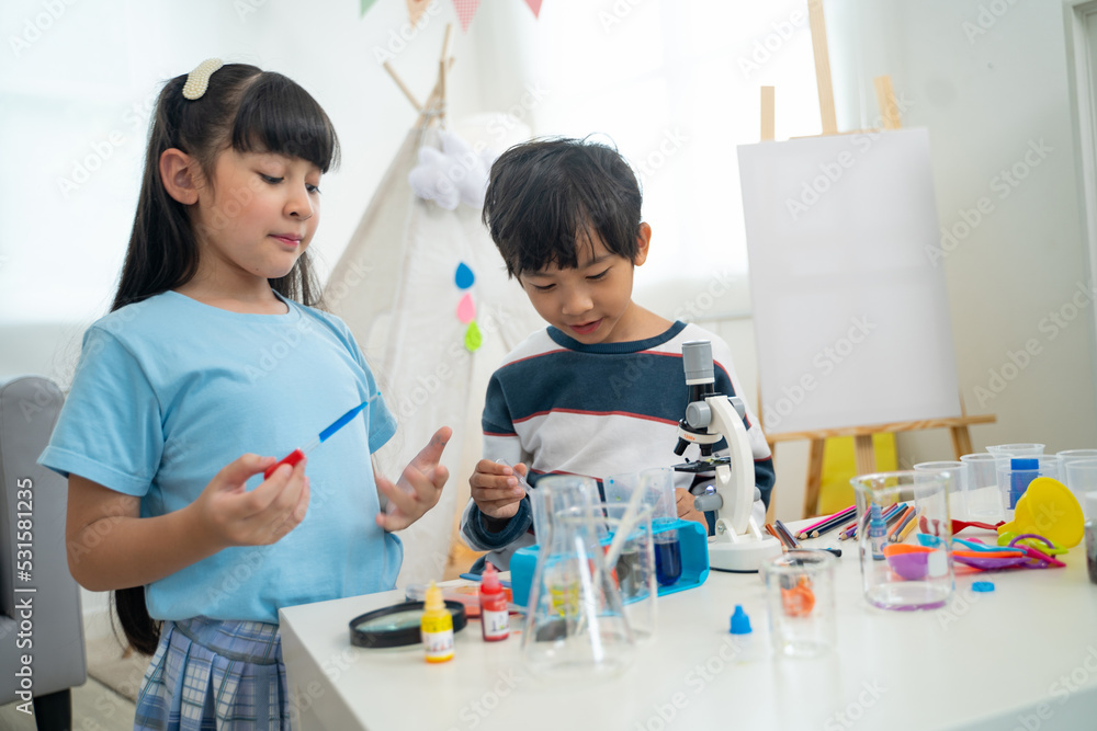 Two little scientists making chemical test with toy microscope in living room Two little scientists making chemical test with toy microscope in living room