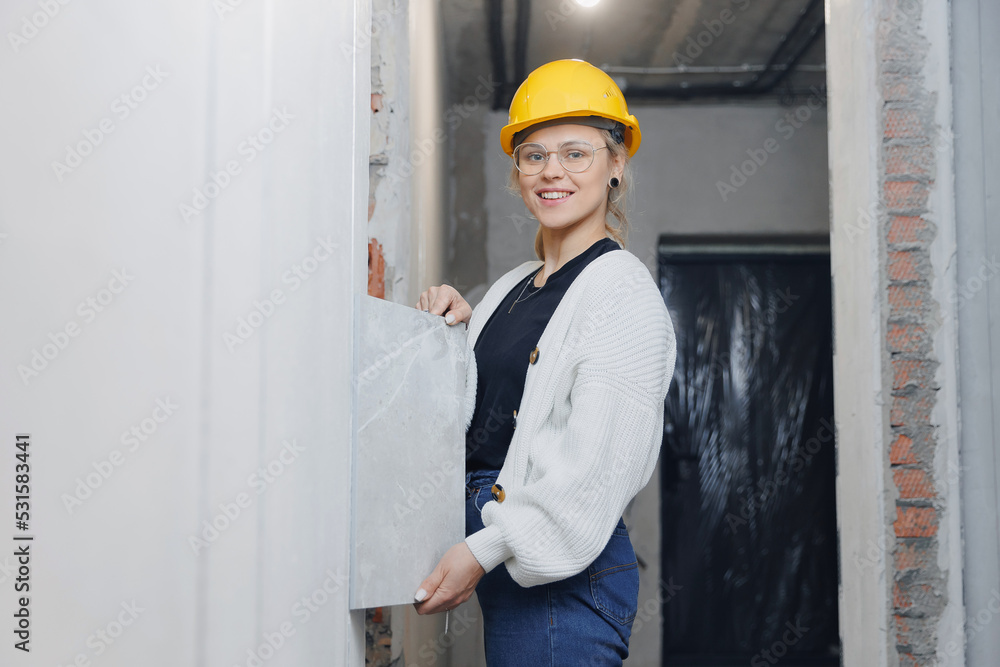 Designer woman checks author supervision builder work in apartment and compares design project with drawings Designer woman checks author supervision builder work in apartment and compares design project with drawings