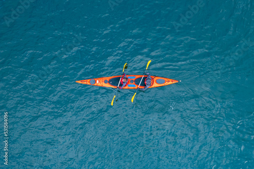 Red kayak boat two rowers on blue turquoise water sea, sunny day. Concept extreme sport, aerial top view