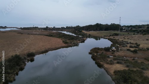 medium altitude drone on a cloudy day slowly rotating over reflective still body of water with birds passing by. photo