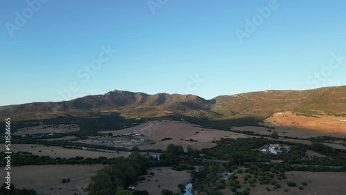 rising up over countryside with farmland half in shadow and mountains in sunlight at sunset. photo