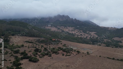 Drone rising up revealing a cloud covered rocky mountain in a Spanish countryside. photo