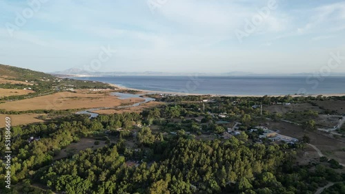 drone travelling slowly over trees towards beach and sea with Morocco in the distance. photo