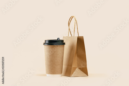 Takeaway paper coffee cup with lunch bag on beige. Snack delivery service. Coffee to go. Grab and go or carry out beverage. Disposable mockup packaging. Place for text. Minimal