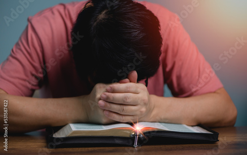 People holding hands head bow down  pray to God in the middle book holy bible book with cross necklace front of the holy bible. photo