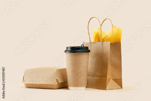 Takeaway paper coffee cup with lunch bag and burger box on beige. Snack delivery service. Coffee to go. Grab and go or carry out beverage. Disposable mockup packaging. Place for text. Minimal