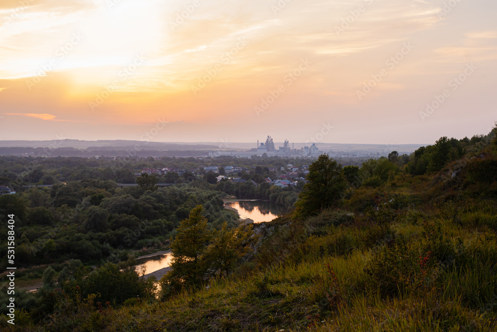 Panoramic view of the city of Ivano-Frankivsk. View of mountain hill and industrial power station oland behind at evening. Sunset over Ivano Frankivsk city in Ukraine. Landscape with hills and river.