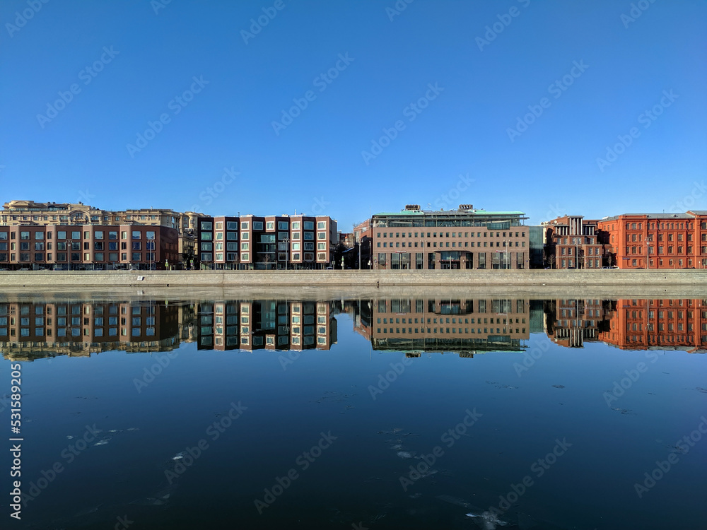 Moscow, Russia - March 01, 2022: Beautiful view of the embankment of the Muzeon park against the blue sky. Houses are reflected in the Moscow River. Copy space