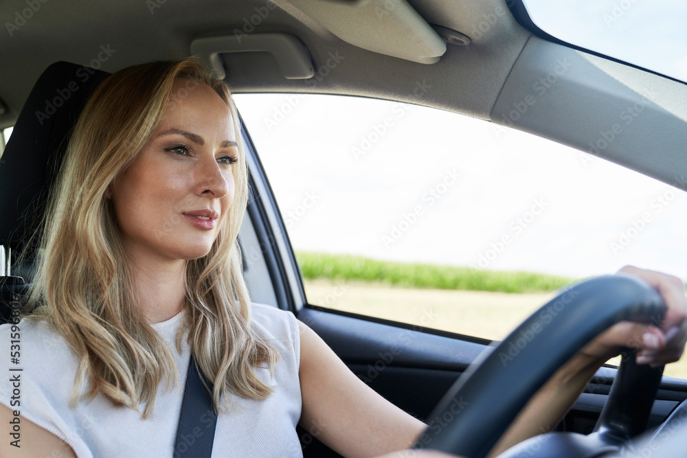 Caucasian adult blonde woman driving a car