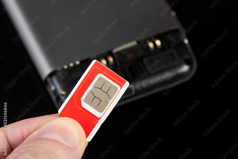 A man holding sim card against the background of a smartphone A man holding sim card against the background of a smartphone