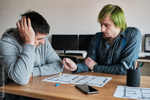 Team of two colleagues interior designers working on architectural project in office.