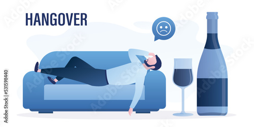 Hangover, unhappy man lies on couch with headache. Health problems after night party. Addiction to alcohol. Large bottle of wine and glass. Excessive alcohol consumption.