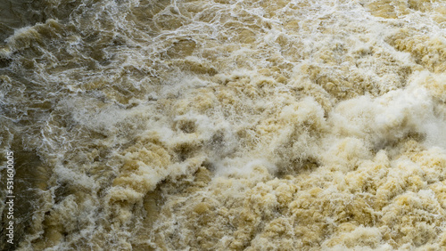 A wave on the seashore as a background. Brown muddy waves break on the shore photo