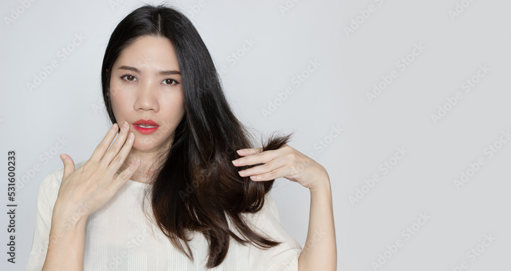 Asian beautiful woman holds and looking her tip hair to see split and dry hair with worry face Asian beautiful woman holds and looking her tip hair to see split and dry hair with worry face