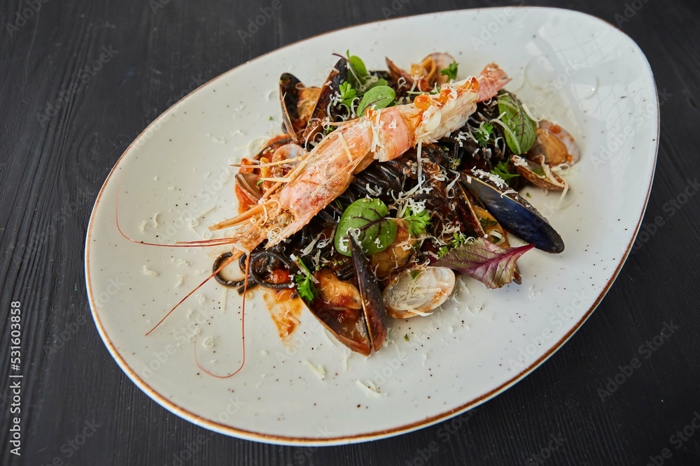 Black pasta with mussels and king shrimp. Food from the chef in a restaurant or cafe. Black pasta with mussels and king shrimp. Food from the chef in a restaurant or cafe.