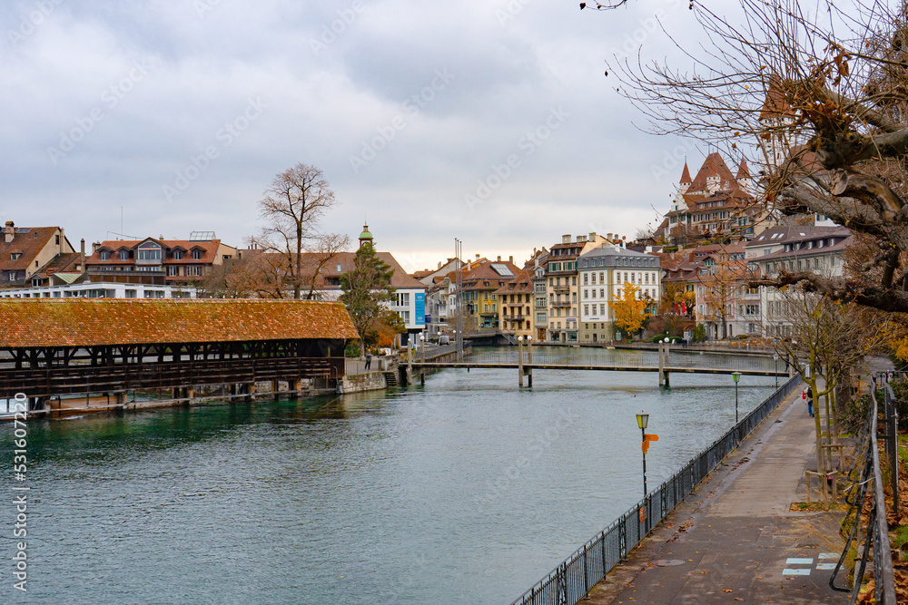 Nice view along Aare lake and wooden bridge in old town of Thun during autumn , winter cloudy day : Thun , Switzerland : December 2 , 2019