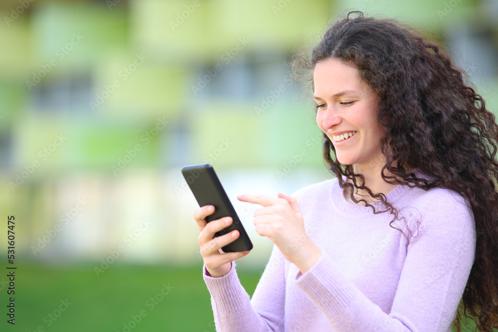 Happy woman walks checking smart phone content in the street Happy woman walks checking smart phone content in the street
