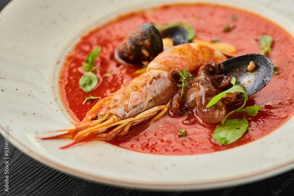 Tomato soup with seafood, shrimp, octopus, mussels and other shellfish for cooking dinner on a black background. Healthy food handmade Tomato soup with seafood, shrimp, octopus, mussels and other shellfish for cooking dinner on a black background. Healthy food handmade
