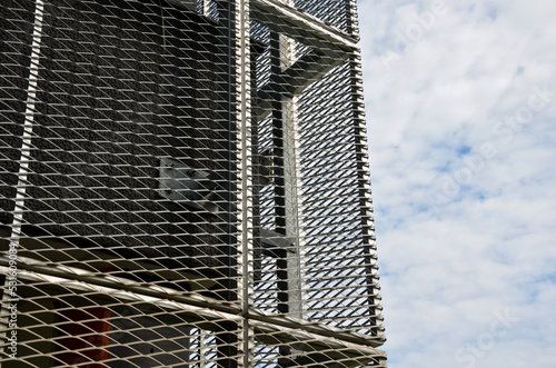 steel cladding of a building with a expanded metal lattice structure. galvanized gray nets protect the industrial building. Blue sky in contrast to a silver background, wall photo