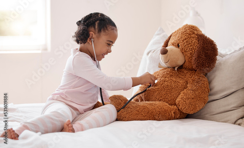 Girl, teddy bear and stethoscope in hospital game in medical, healthcare and wellness bedroom. Happy smile, curious orphan child or fun patient in medicine play activity in pediatric community center