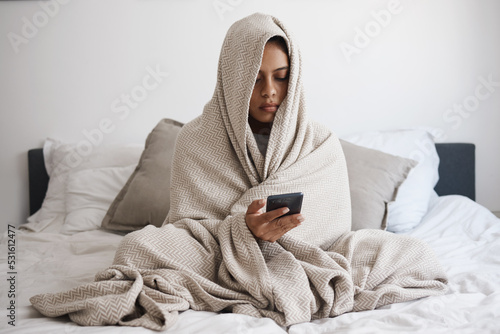 Depression, anxiety and woman texting in bed, reading online social media bullying post, feeling alone in bedroom. Mental health, fear and sad female looking unhappy, vulnerable in emotional crisis photo