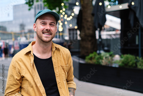 Smiling man wearing cap and unbuttoned shirt