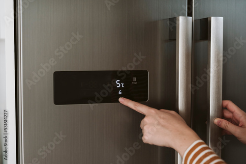 Close-up of woman adjusting cooling temperature at fridge