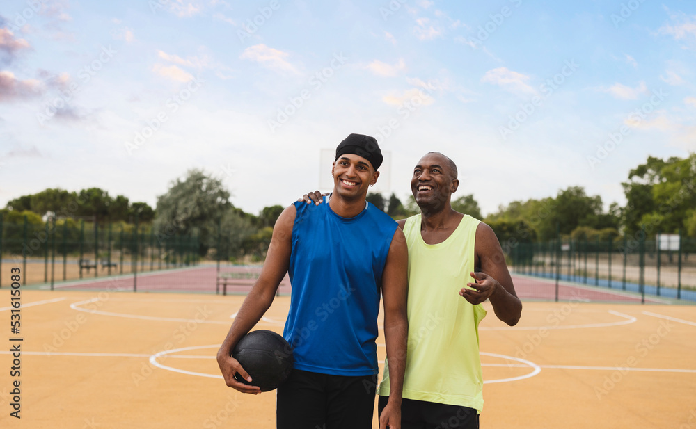 Smiling father talking with son gesturing at basketball court Smiling father talking with son gesturing at basketball court