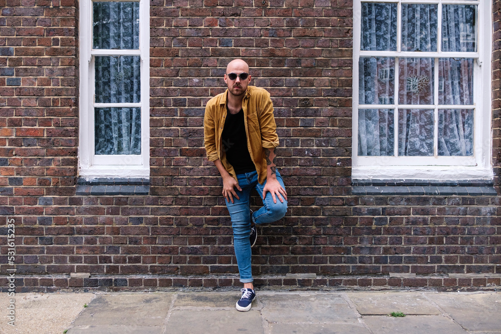 Man wearing sunglasses leaning on brick wall Man wearing sunglasses leaning on brick wall