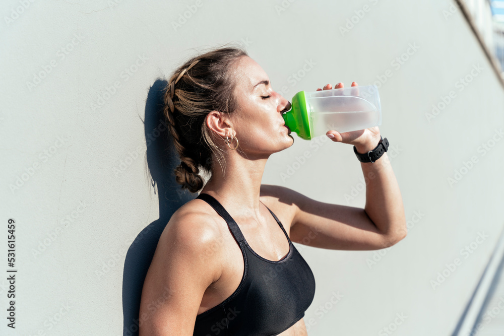 Woman drinking water from bottle on sunny day Woman drinking water from bottle on sunny day