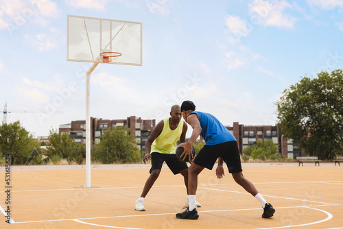 Father playing basketball with son defending at court