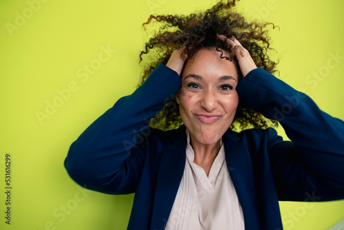 Playful businesswoman with hands in curly hair photo