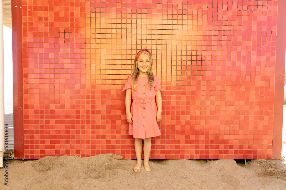 Happy cute girl standing in front of wall at beach Happy cute girl standing in front of wall at beach