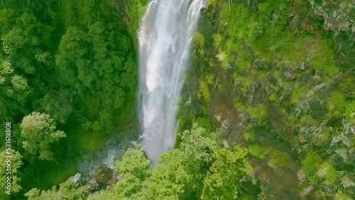 Roaring waterfall plunges into a ravine surrounded by a verdant rainforest photo