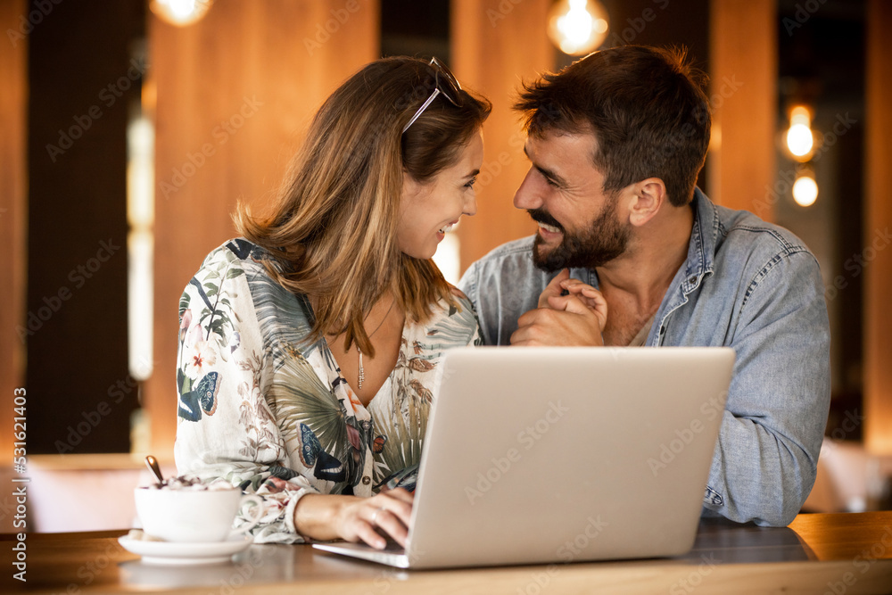 Happy couple using laptop at cafe enjoying time together Happy couple using laptop at cafe enjoying time together