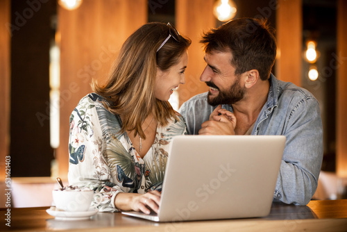 Happy couple using laptop at cafe enjoying time together