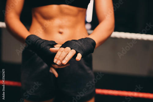 Female athlete wrapping her hands in a boxing ring