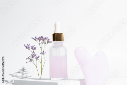 Pink Gua Sha facial massage tools. Rose Quartz jade scrapper and beauty facial oil on white background. Anti age, lifting and toning treatment at home.