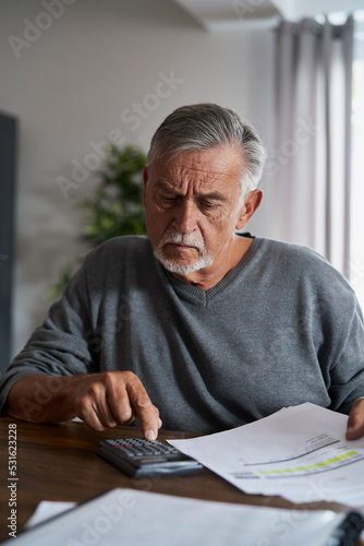 Senior man counting home budget at the calculator