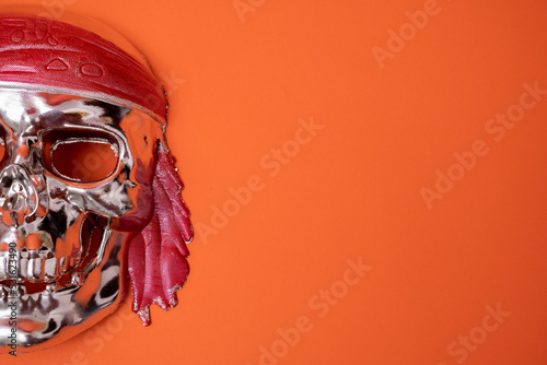 Fototapeta a silver skull with a red headband on a red background